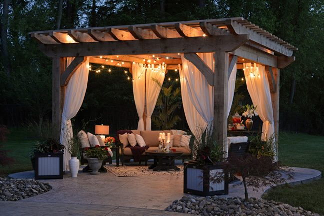 A gazebo at dusk with warm lighting and outdoor seating