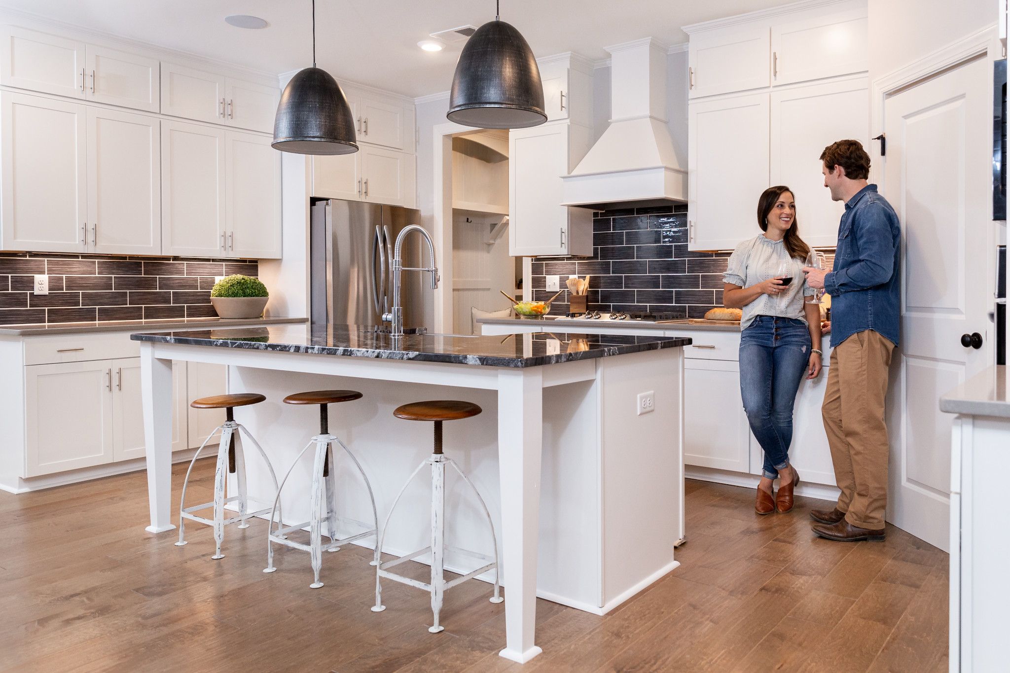 A couple standing in the kitchen of their manufactured home carries on a conversation while holding coffee mugs. Their kitchen looks the same as the kind you’d find in a traditional, stick-built home.