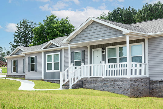  A gray single-story home with white porch trim. The home’s lawn is verdant and looks well kept.