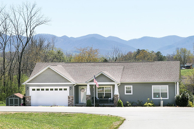 A slate grey manufactured home with an attached two-car garage