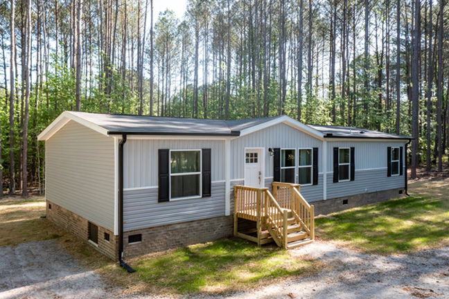 A manufactured home with an off-white and grey exterior with wooden front porch steps